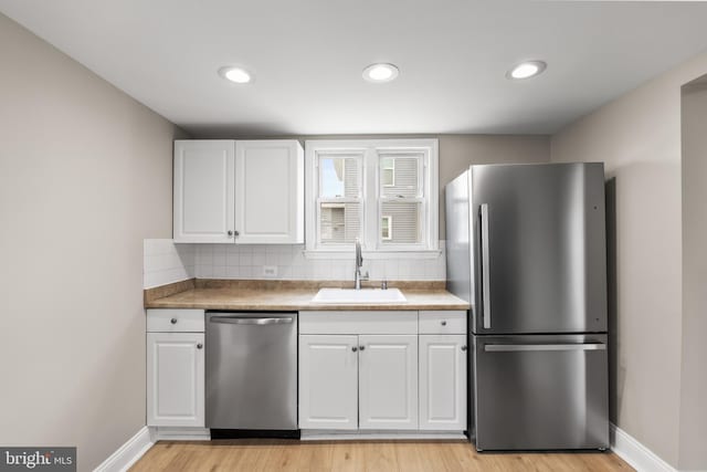 kitchen featuring light countertops, appliances with stainless steel finishes, a sink, and white cabinetry