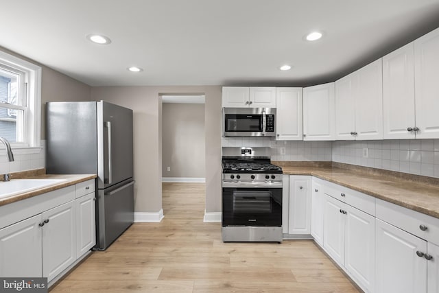 kitchen with white cabinetry, appliances with stainless steel finishes, light countertops, and a sink