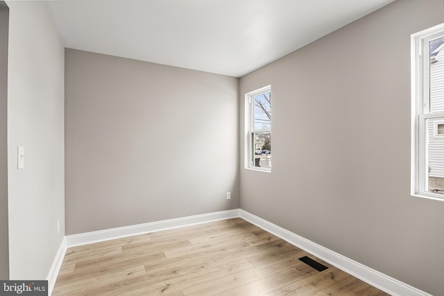 empty room featuring light wood-type flooring, visible vents, and baseboards