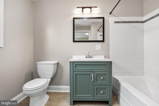 full bath featuring bathing tub / shower combination, toilet, vanity, wood finished floors, and baseboards