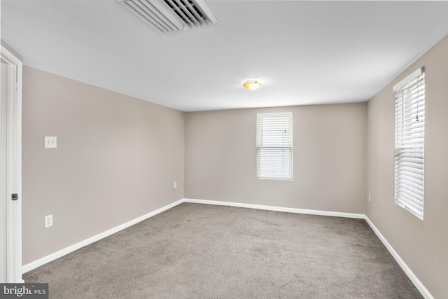 empty room featuring carpet, visible vents, and baseboards