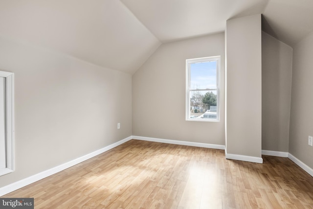 additional living space featuring vaulted ceiling, light wood-style flooring, and baseboards