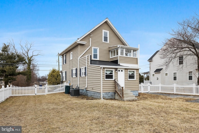 rear view of house with entry steps, fence private yard, central AC, and a yard