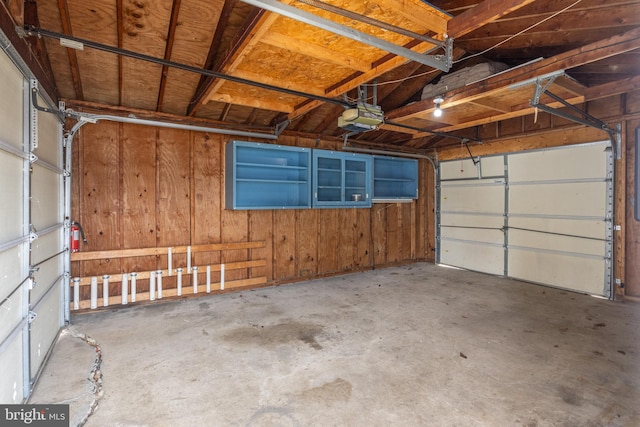 garage featuring a garage door opener and wood walls