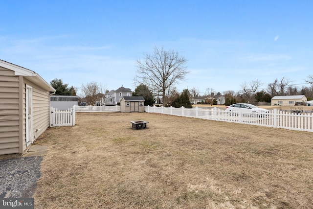 view of yard with an outdoor fire pit, a fenced backyard, and a residential view