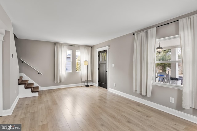 foyer with light wood-style flooring, baseboards, and stairs