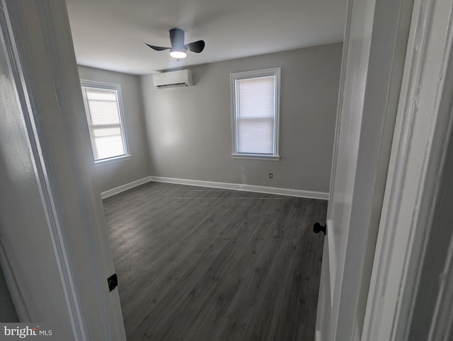 spare room with ceiling fan, dark wood-type flooring, a wall mounted AC, and baseboards