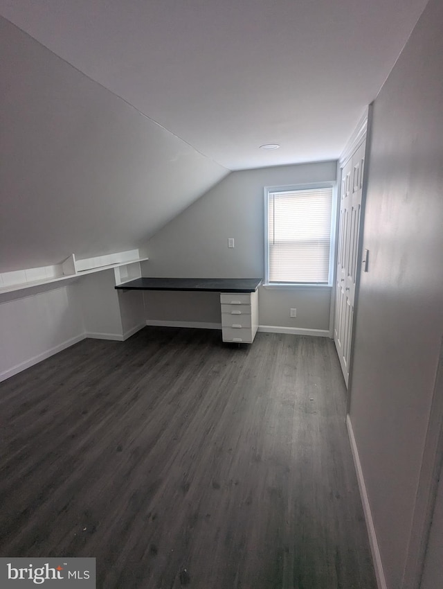 bonus room with dark wood-type flooring, vaulted ceiling, and baseboards