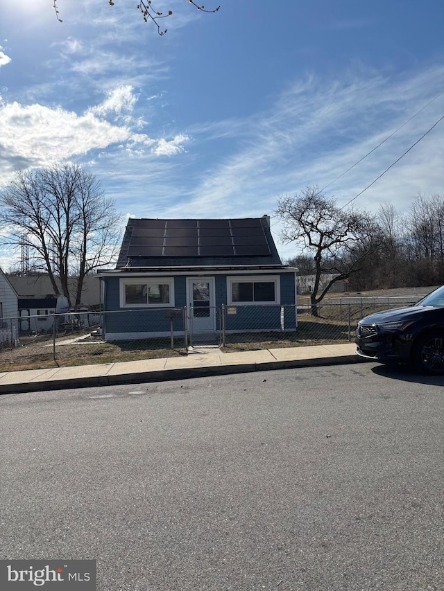 view of front facade featuring a fenced front yard and roof mounted solar panels