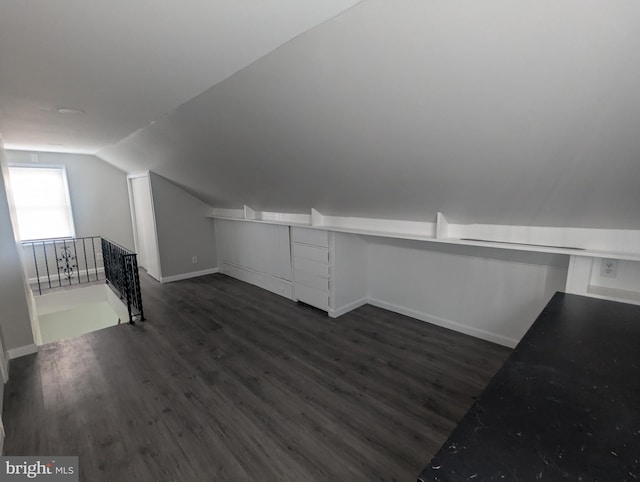 bonus room featuring lofted ceiling, dark wood-style flooring, and baseboards