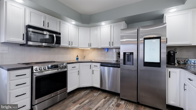 kitchen with stainless steel appliances, dark countertops, and white cabinetry