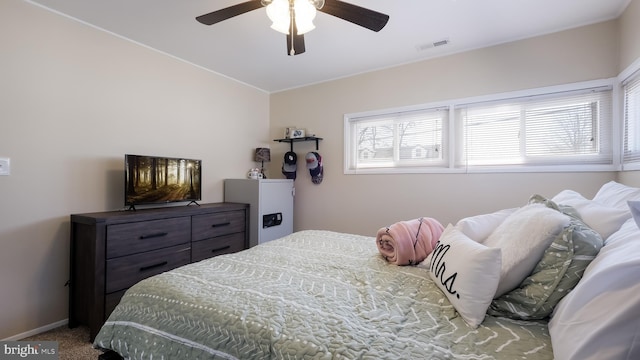 carpeted bedroom featuring a ceiling fan, visible vents, and baseboards