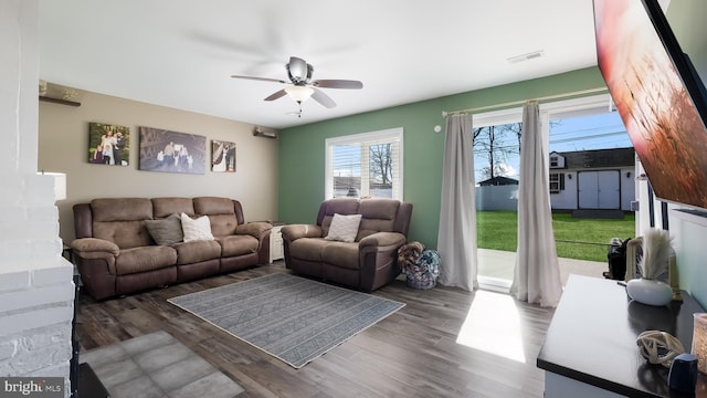 living area with dark wood-type flooring, visible vents, and a ceiling fan