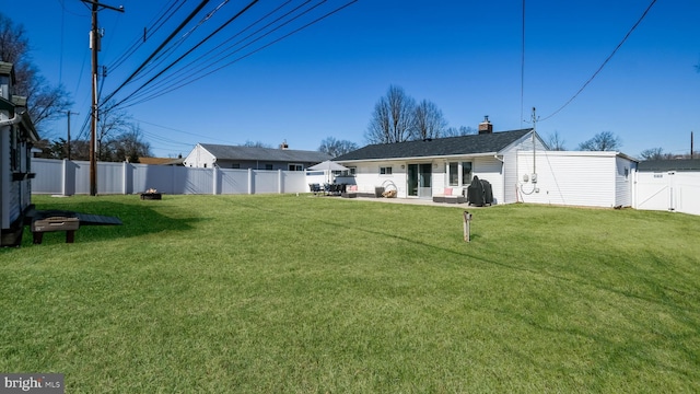 back of house featuring a patio area, a fenced backyard, a yard, and a chimney