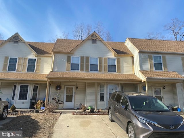 townhome / multi-family property with covered porch and a shingled roof