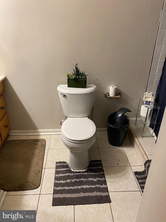 bathroom with toilet, tile patterned flooring, vanity, and baseboards