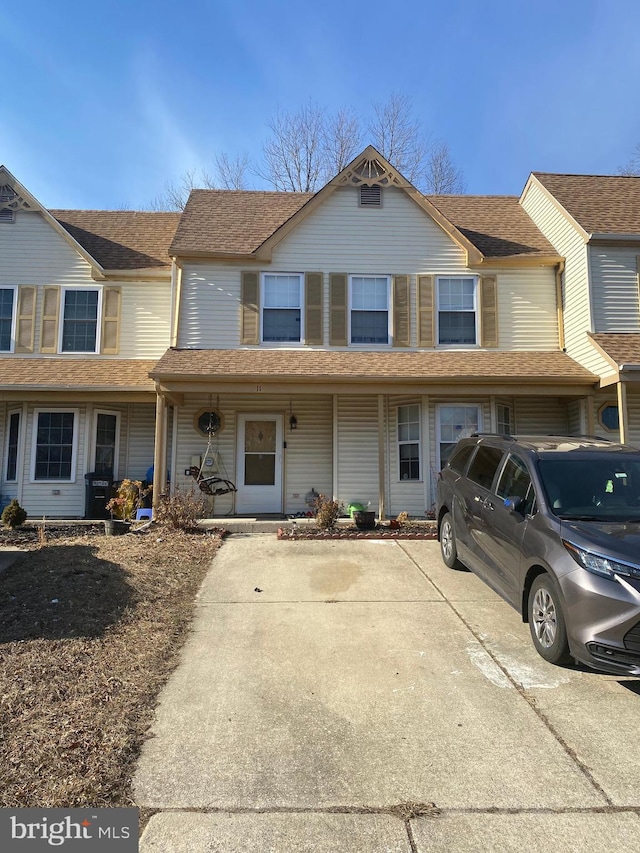 townhome / multi-family property featuring covered porch, roof with shingles, and driveway