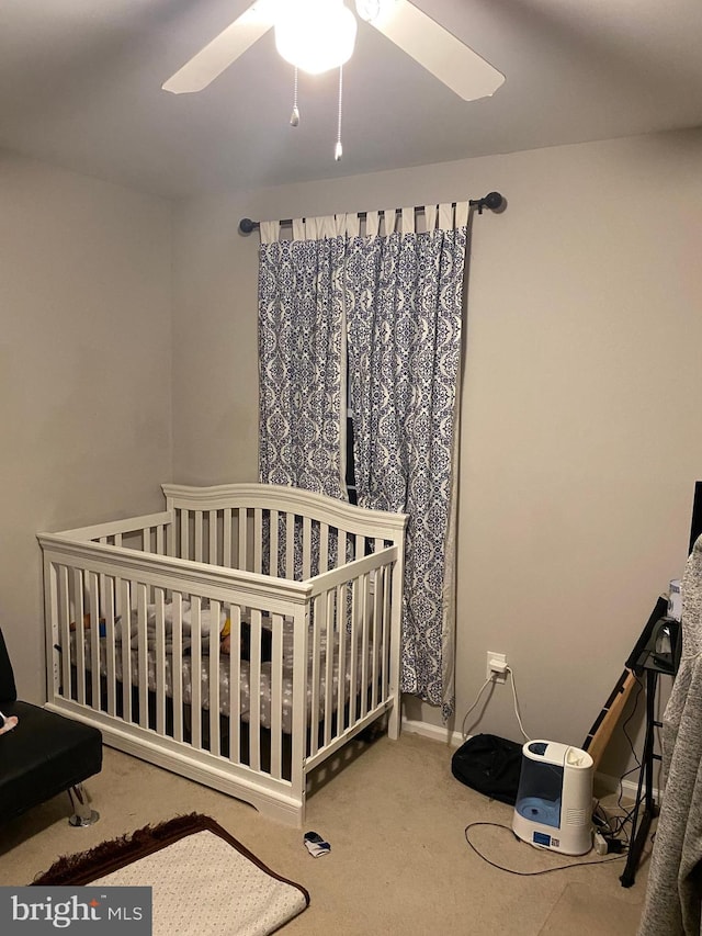 bedroom with a crib, carpet, and a ceiling fan