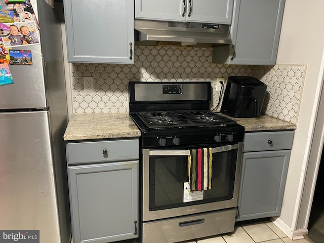 kitchen featuring stainless steel appliances, light countertops, decorative backsplash, gray cabinetry, and under cabinet range hood