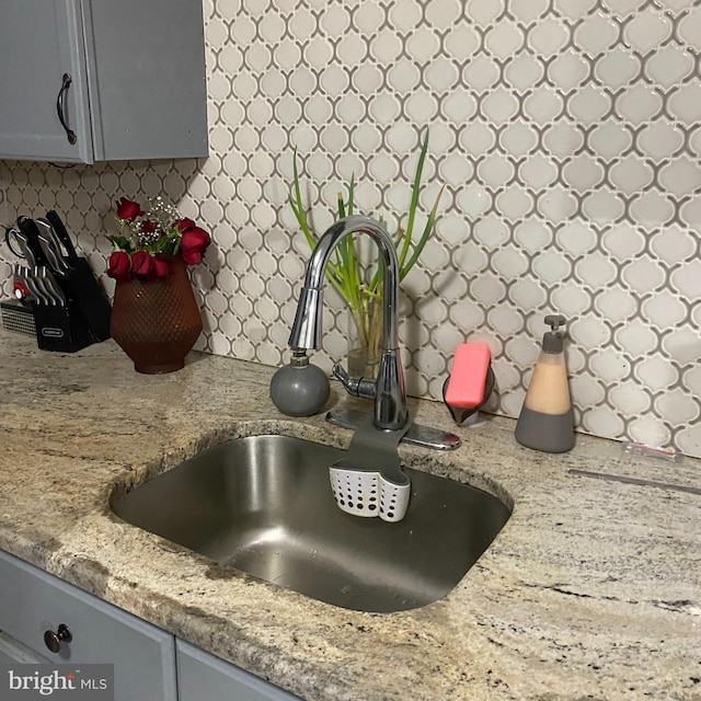 room details with light countertops, tasteful backsplash, gray cabinets, and a sink