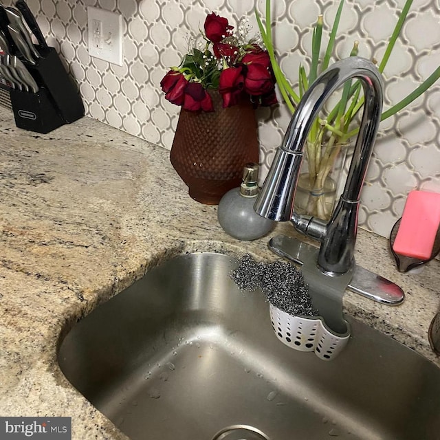 interior details featuring light stone counters and a sink