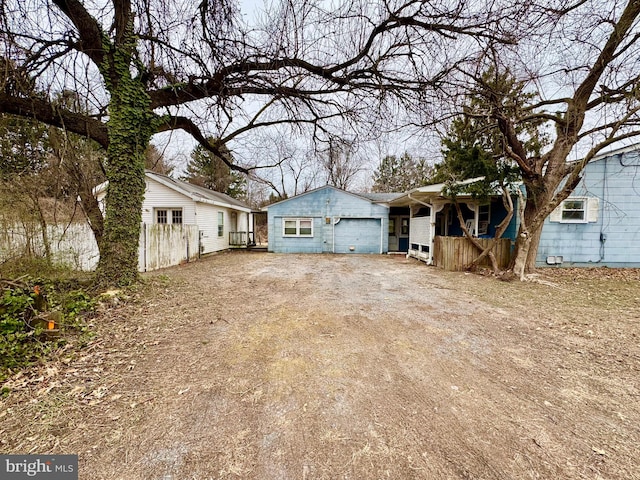 exterior space with dirt driveway, covered porch, an attached garage, and fence