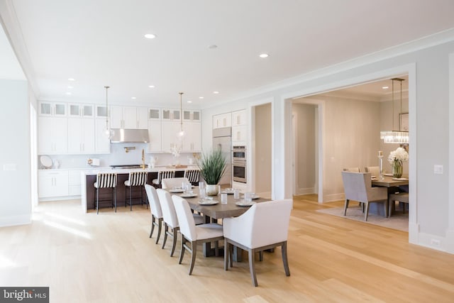 dining area featuring light wood-style floors, crown molding, and recessed lighting