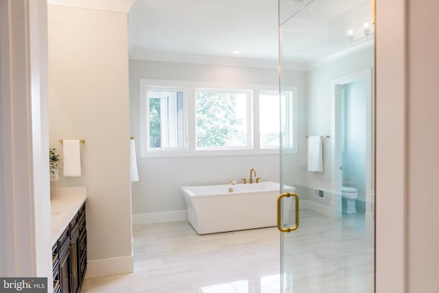 full bath with toilet, a freestanding tub, ornamental molding, and vanity