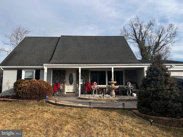 view of front facade featuring a front yard, stone siding, and roof with shingles