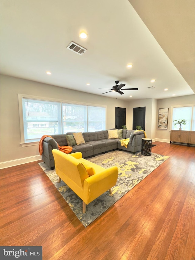 living room with recessed lighting, visible vents, baseboards, and wood finished floors