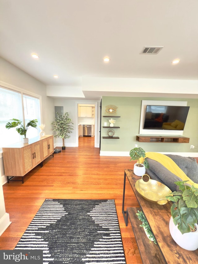 living area with recessed lighting, visible vents, baseboards, and wood finished floors