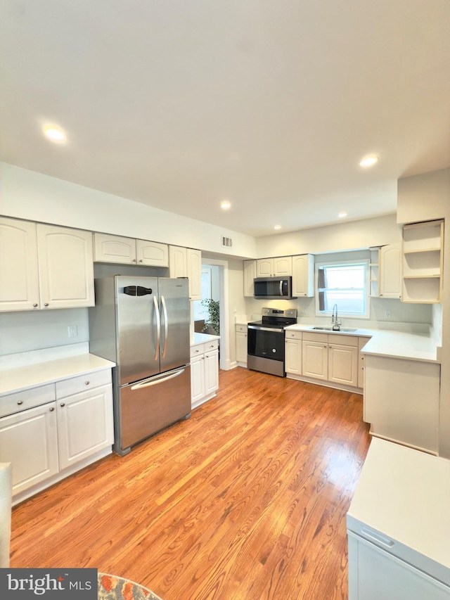 kitchen with visible vents, light wood finished floors, a sink, light countertops, and appliances with stainless steel finishes