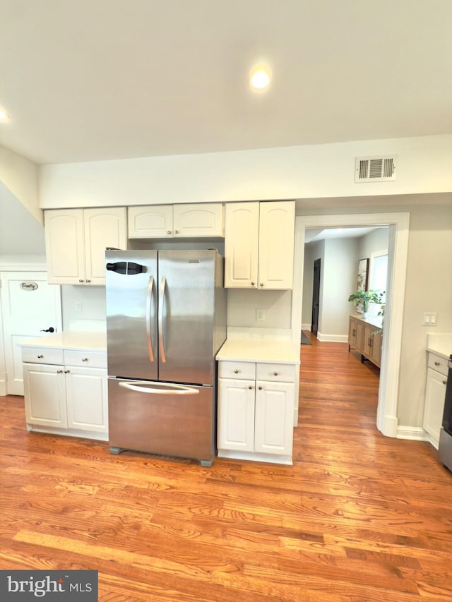 kitchen featuring light wood finished floors, visible vents, light countertops, and freestanding refrigerator