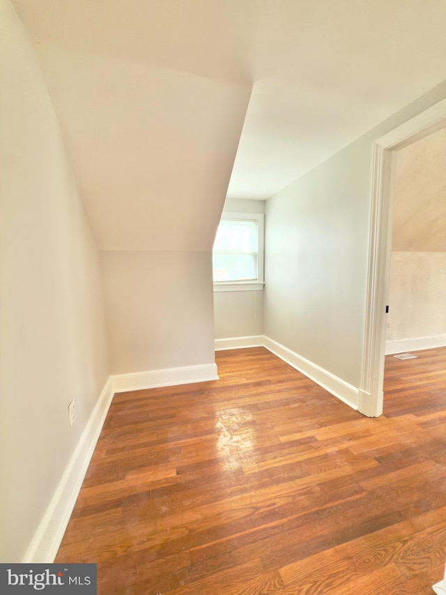 bonus room featuring vaulted ceiling, baseboards, and wood finished floors