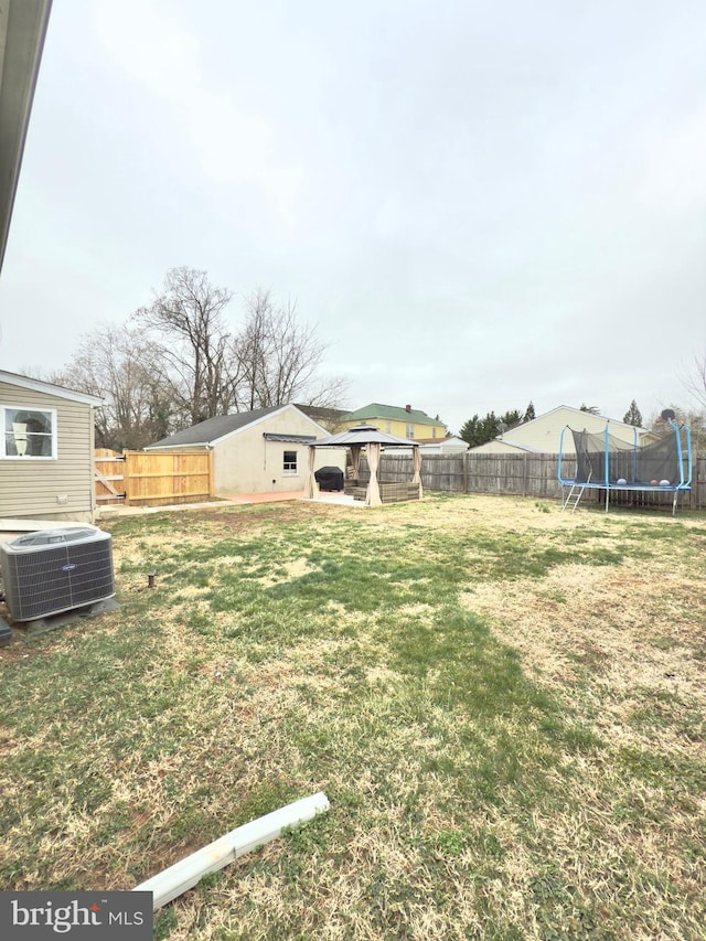 view of yard featuring a gazebo, a trampoline, central AC unit, and a fenced backyard