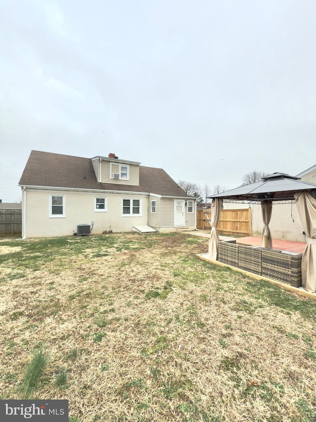 back of property featuring a gazebo, a lawn, central AC unit, and a fenced backyard