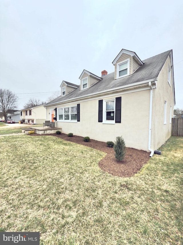 view of side of property featuring a lawn, fence, and stucco siding