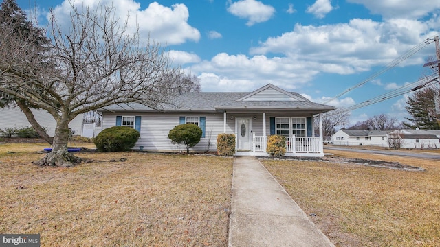 view of front of home with covered porch, a front lawn, and roof with shingles