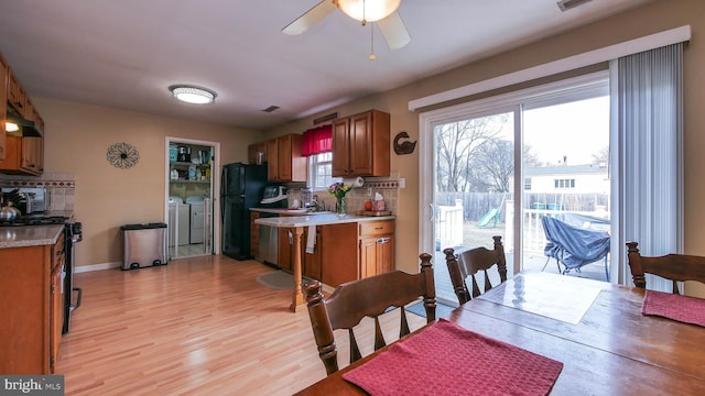 dining space with washer and clothes dryer, light wood finished floors, visible vents, ceiling fan, and baseboards