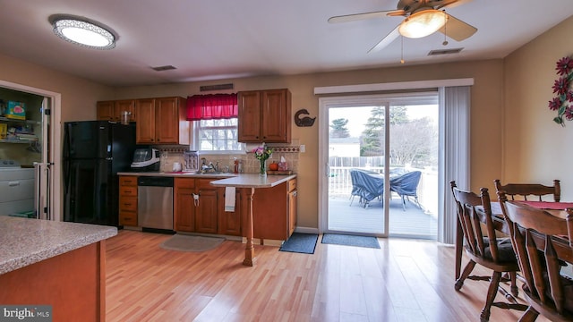 kitchen featuring light countertops, freestanding refrigerator, dishwasher, brown cabinetry, and washer / dryer