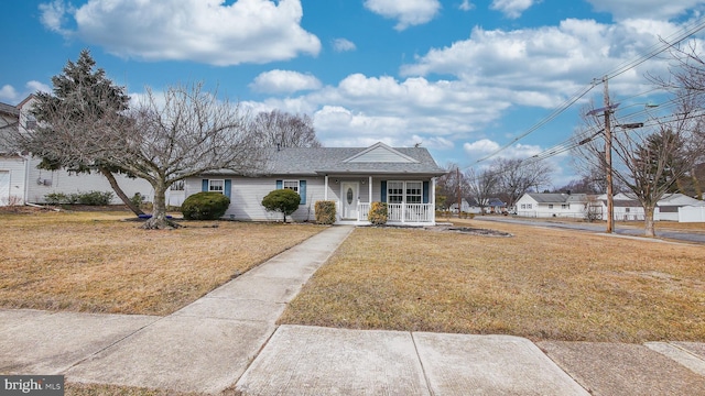 view of front of home with covered porch, roof with shingles, and a front yard