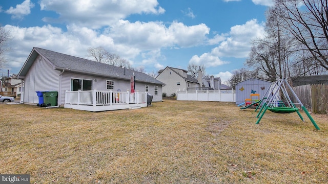 view of yard featuring fence, a deck, and a playground