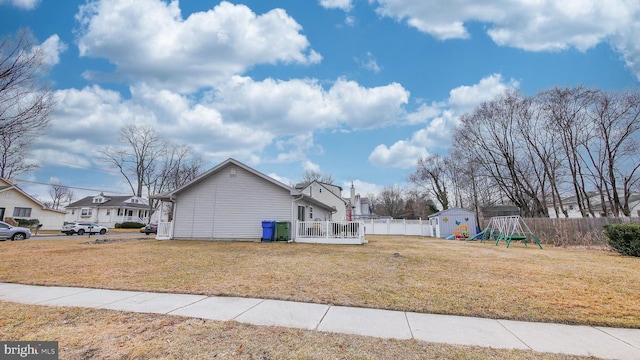 view of side of home featuring a yard, a residential view, fence, and a storage shed