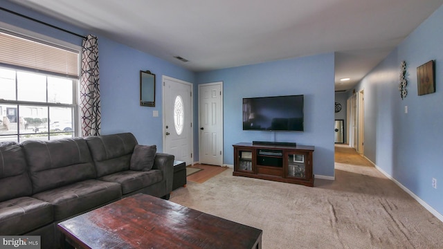 living area featuring visible vents, baseboards, and light colored carpet