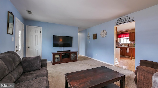 living room featuring light carpet, visible vents, and baseboards