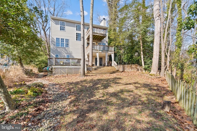 rear view of house featuring a chimney, fence, and a balcony