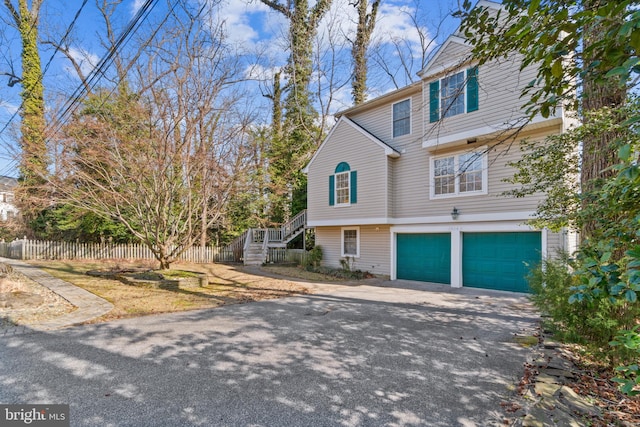 view of front facade featuring stairs, driveway, fence, and a garage