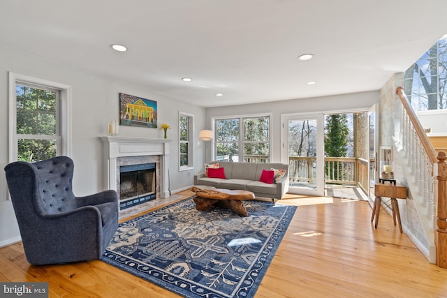 living area with stairs, recessed lighting, a fireplace with flush hearth, and wood finished floors