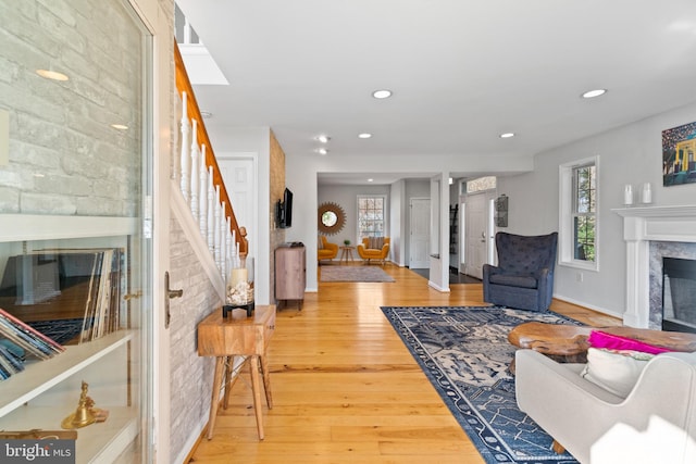 living area featuring stairs, wood finished floors, a high end fireplace, and recessed lighting