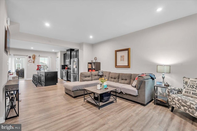 living room with recessed lighting, light wood-style flooring, and baseboards